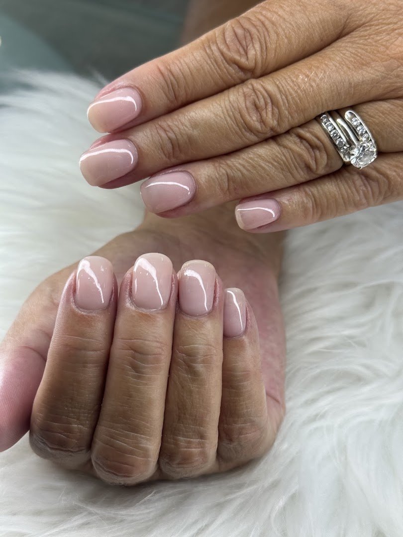 Manicured hands with glossy nails on a salon table.